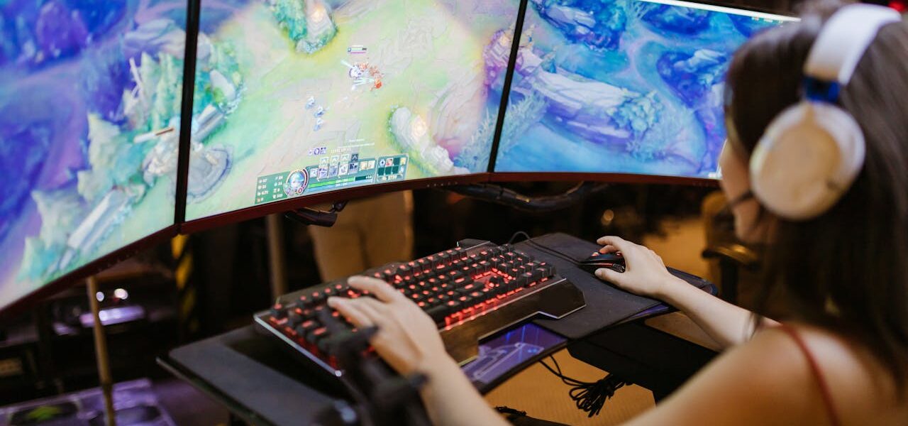 a woman playing League of Legends on three-monitor PC setup